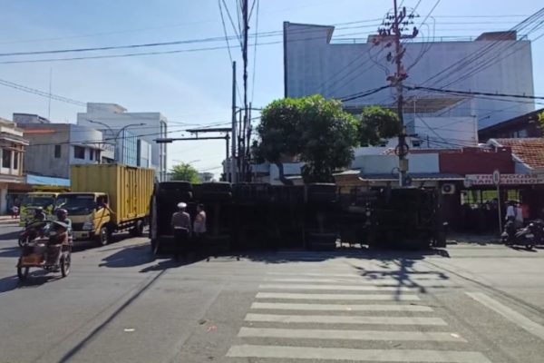 Badan truk muatan garam yang dikemudikan Udas Warga Jombang 21 tahun terguling di Simpang Kapasan.