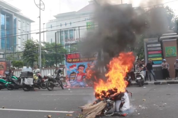 Massa AMI melakukan aksi bqkar spanduk dan kayu, sebagai bentuk protes atas penanganan kasus korupsi Eks Jampidsus Febrie Adriansyah di Kejati Jatim.