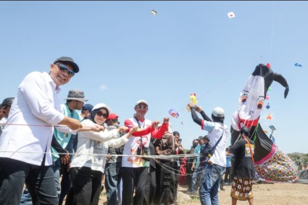 Eri Cahyadi dan istri mencoba menerbangkan layang-layang hias Punakawan dalam Kite Festival 2026.
