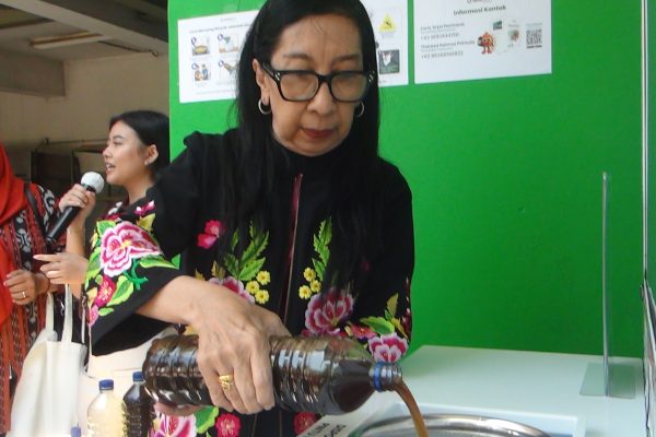 Salah satu warga menuangkan minyak jelantah ke Reverse Vending Machine U Collect.