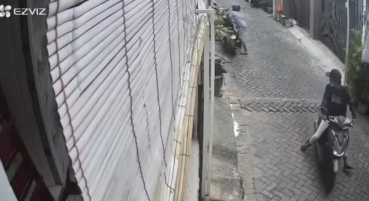 Rekaman CCTV di Margorukun memperlihatkan satu pelaku curanmor beraksi mengenakan kaos biru, sementara pelaku lainnya yang mengenakan topi mengamati situasi.