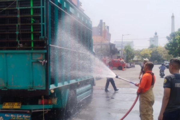 Petugas DPKP Surabaya menyemprotkan air ke truk pengangkut ayam untuk mencegah ayam kepanasan akibat suhu tinggi yang dipicu fenomena angin baratan.